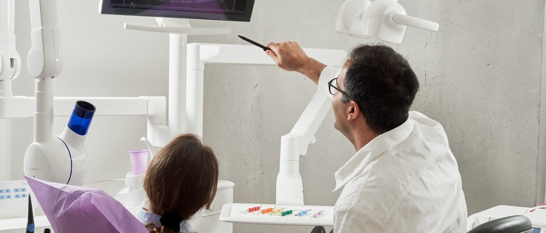 Dentist explaining an X-ray on a screen to a patient in the dental chair