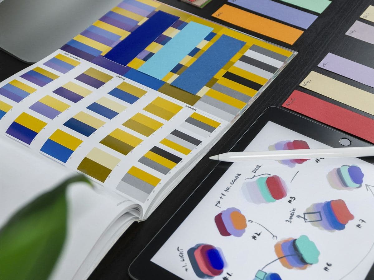 Color swatch book and brand palette samples on a designer's desk