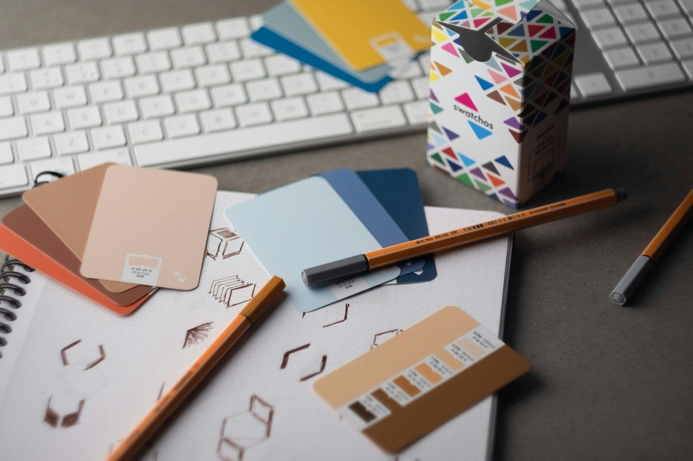 Brand identity color samples and sketches on a designer's desk