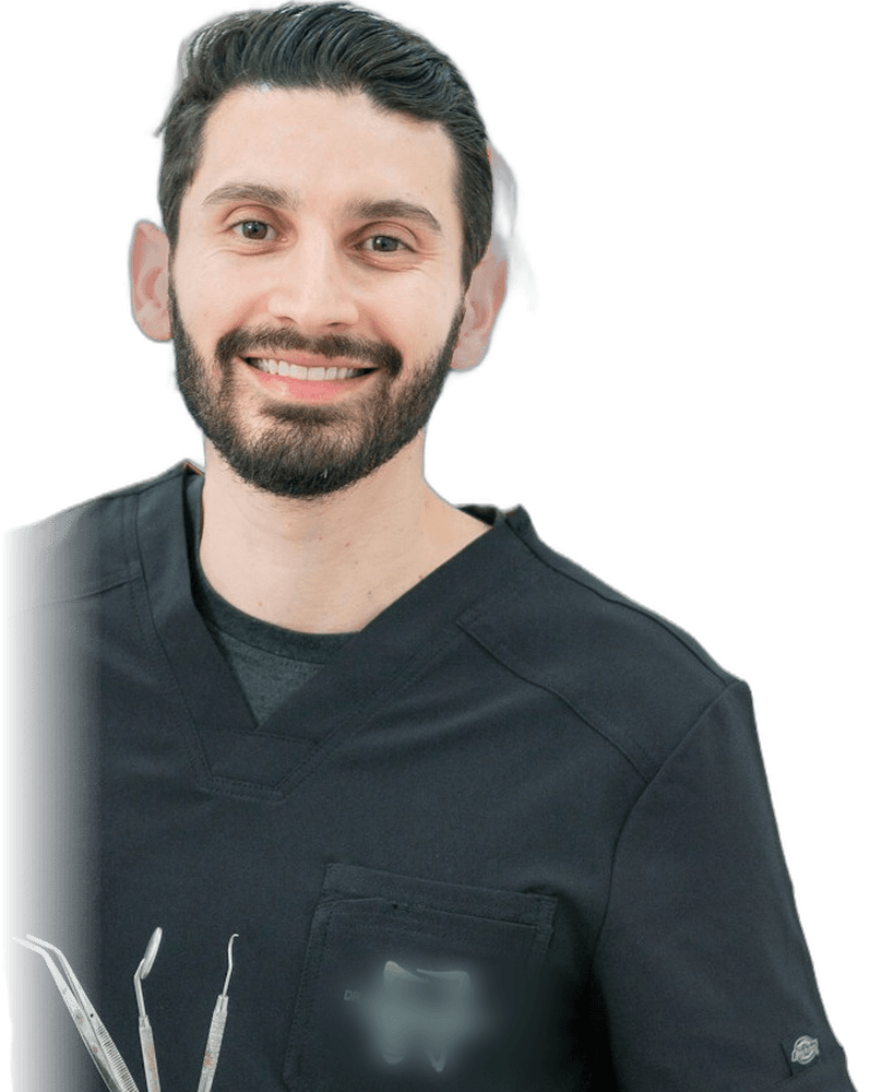 Smiling dentist in scrubs holding dental instruments