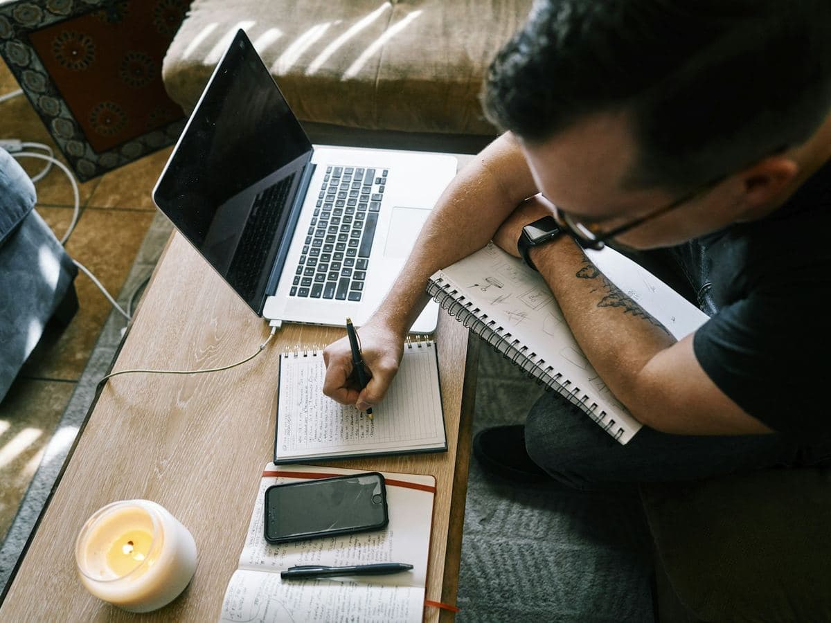 Writer drafting an article with a laptop and notebook