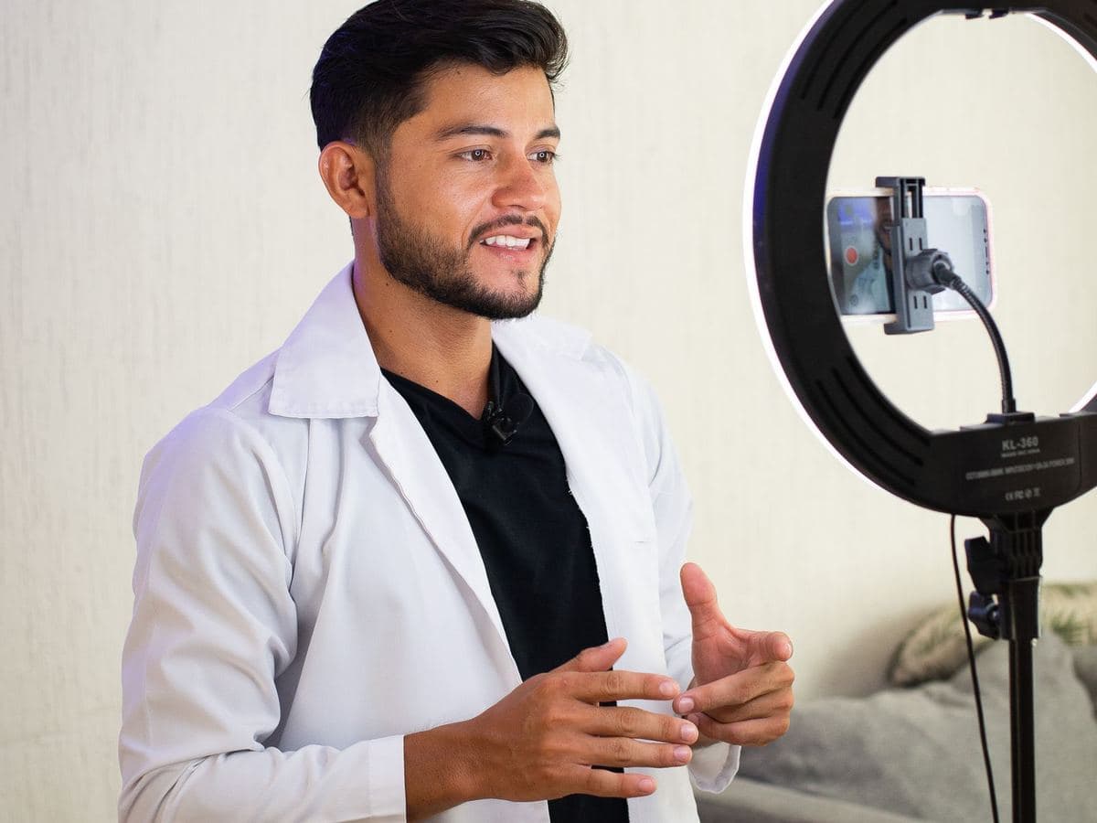 Doctor in a white coat recording a video with a ring light